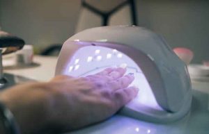 UV lamp gel polish manicure process. Salon procedure. The master coats the client's nails with a varnish.